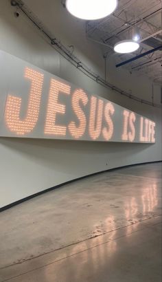 a large sign with the words jesus is life on it in an empty room next to some lights