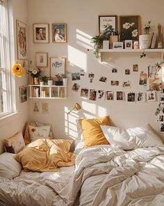 an unmade bed in a bedroom with pictures on the wall and shelves above it