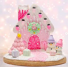 a pink and white gingerbread house with snowmen around it