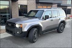 a silver and black suv parked in front of a building