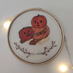 two pumpkins sitting on top of each other in a hoop with string lights around them