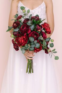 a woman holding a bouquet of red flowers