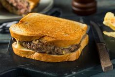 a close up of a sandwich on a plate with chips and a knife next to it