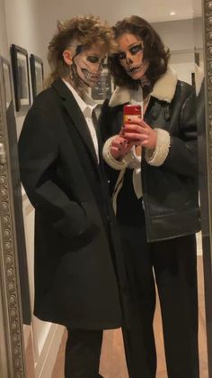 two people dressed up in costumes taking a selfie with their cell phone while standing next to each other