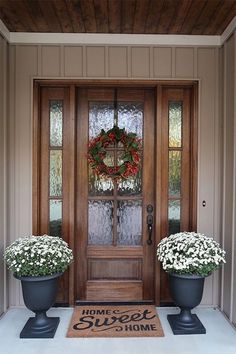 two large planters with wreaths on the front door