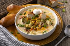 a white bowl filled with soup and topped with sour cream, broccoli, cheese and green onions