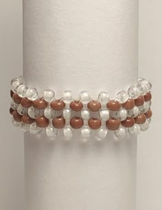 a white and brown beaded bracelet on a stand