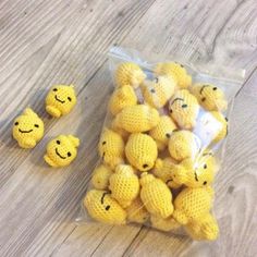 small yellow crocheted smiley faces are in a plastic bag on the floor next to it's contents