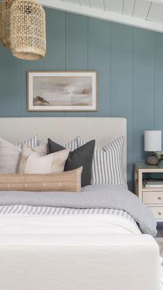 a bedroom with blue walls and white bedding, two nightstands and a wicker basket hanging from the ceiling