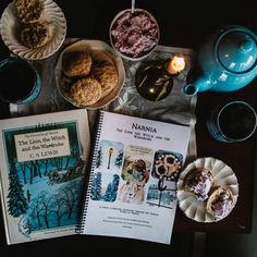 an open book sitting on top of a table next to two plates and bowls filled with food