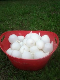 a red bucket filled with white eggs in the grass