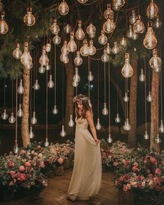 a woman in a white dress standing under a chandelier filled with light bulbs