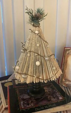 a christmas tree made out of book pages on top of a pile of other books