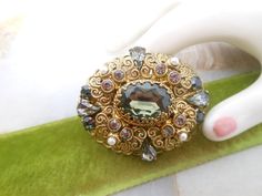 Vintage treasure.. Renaissance Revival brooch. Ornate filigree pin. Gray green glass stone. (Can appear more black in darker light) Rhinestone and faux pearl. Designer - West Germany Length  2" oval. No signs of wear. Lovely vintage condition. MORE brooches here: https://www.etsy.com/shop/VivianJoel?ref=seller-platform-mcnav&section_id=23306305 MORE everything VivianJoel here: https://www.etsy.com/shop/vivianjoel Desired cleaning is left to new owner.   Still uncertain about size?   Compare to p Pearl Pin, Jewelry Lookbook, Enamel Flower, Rhinestone Jewelry, West Germany, Gray Green, Green Glass, Faux Pearl, Light In The Dark