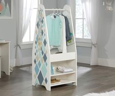 a white rack with clothes and shoes on it in front of a window next to a rug