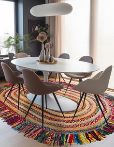 a white table with four chairs and a rug on the floor in front of it