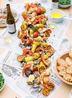 a table topped with lots of different types of food next to wine bottles and glasses