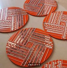 four orange and silver coasters sitting on top of a table next to each other