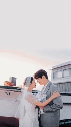 a bride and groom standing in front of a boat