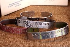 three bracelets with names on them sitting next to a box and some other items