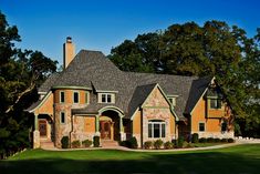 a large house in the middle of a green field with trees and grass around it