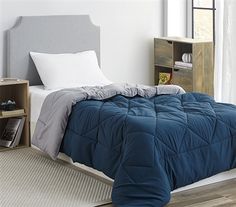 a bed with a blue comforter and pillows on top of it in a bedroom