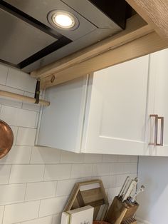 a kitchen with white cupboards and wooden utensils on the counter top,