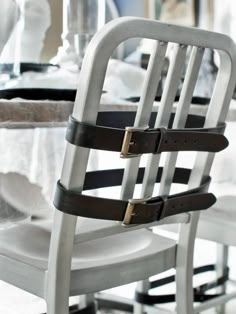 the back of a white chair with black leather straps on it's seatbelts