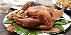 a roasted turkey on a white plate with green leaves