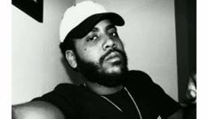 a black and white photo of a man with a beard wearing a baseball cap looking off to the side