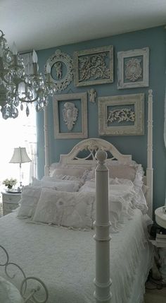 a white bed in a room with pictures on the wall and chandelier above it