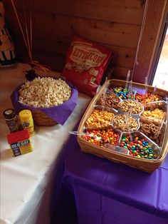 a table topped with lots of food next to a purple table cloth covered tablecloth