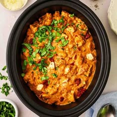 a black bowl filled with food next to other dishes