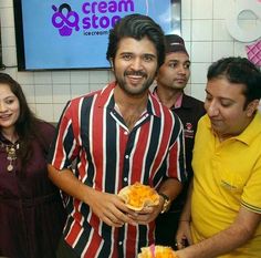 a man holding food in his hands while standing next to two women and one man