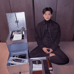 a man sitting on the floor in front of an open box with items inside it