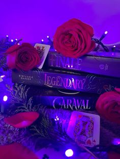 three books stacked on top of each other in front of purple lights and roses with candles