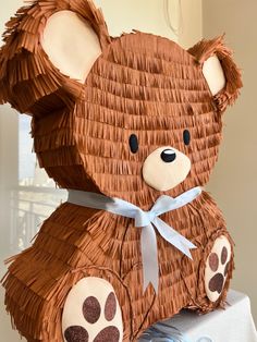 a large brown teddy bear sitting on top of a table next to a blue ribbon