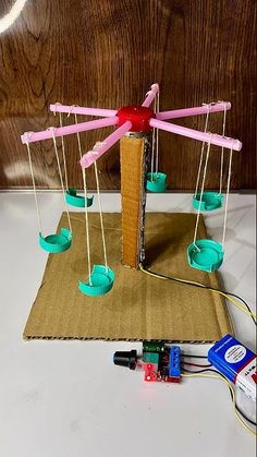 an object made out of toothpicks and wires on a piece of cardboard with other items around it