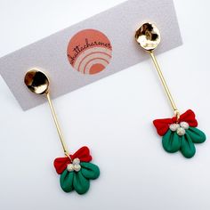 pair of green and red flower shaped earrings with gold posts on white card for sale