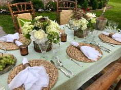 a table set with place settings and flowers in vases on top of the table