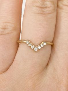 a woman's hand wearing a gold ring with three diamonds