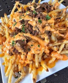 a white plate topped with french fries covered in cheese and meat toppings on top of it