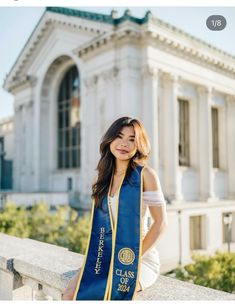 a woman wearing a blue and gold sash standing in front of a white building with columns