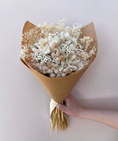 a hand holding a bouquet of dried flowers