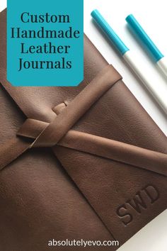 the custom handmade leather journal is shown with two pens