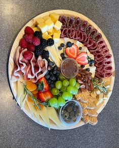 a platter filled with different types of cheeses and fruit on top of a table