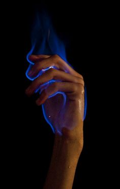 a hand holding something with blue flames coming out of it