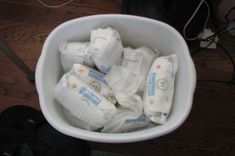 a white bowl filled with lots of diapers on top of a wooden table next to headphones