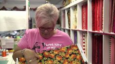 a woman in a pink shirt is looking at an item