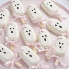 marshmallows with faces are arranged on a pink plate and tied in ribbons